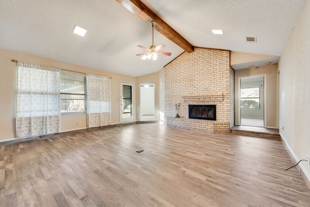 unfurnished living room featuring a fireplace, a textured ceiling, light hardwood / wood-style floors, and a wealth of natural light