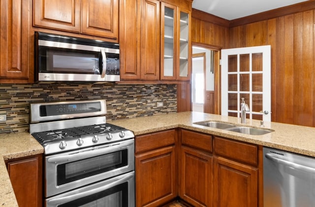 kitchen with light stone countertops, decorative backsplash, sink, and stainless steel appliances