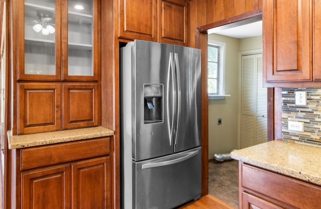 kitchen featuring tasteful backsplash, light stone countertops, and stainless steel fridge with ice dispenser