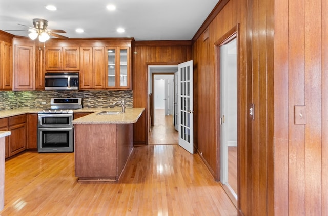 kitchen with ceiling fan, sink, tasteful backsplash, appliances with stainless steel finishes, and light wood-type flooring