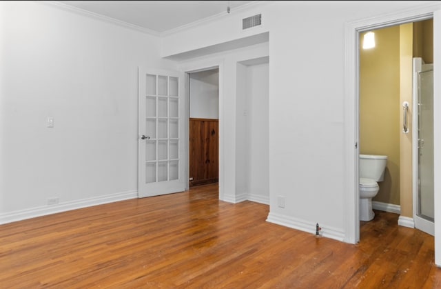 unfurnished bedroom with ornamental molding, ensuite bath, and hardwood / wood-style floors