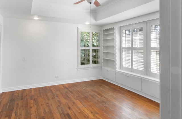 spare room with ornamental molding, a tray ceiling, dark hardwood / wood-style flooring, and ceiling fan