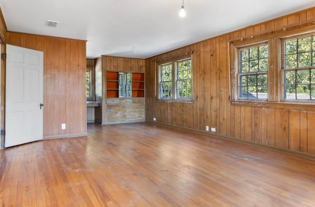 unfurnished living room with wooden walls and light hardwood / wood-style floors