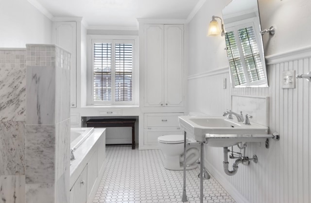 bathroom with tile patterned floors, crown molding, toilet, and a tub