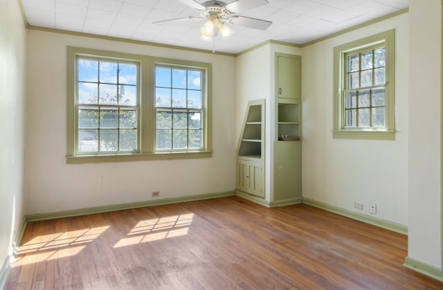 unfurnished room with wood-type flooring, crown molding, ceiling fan, and a healthy amount of sunlight