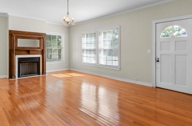 unfurnished living room with a notable chandelier, crown molding, and light hardwood / wood-style flooring