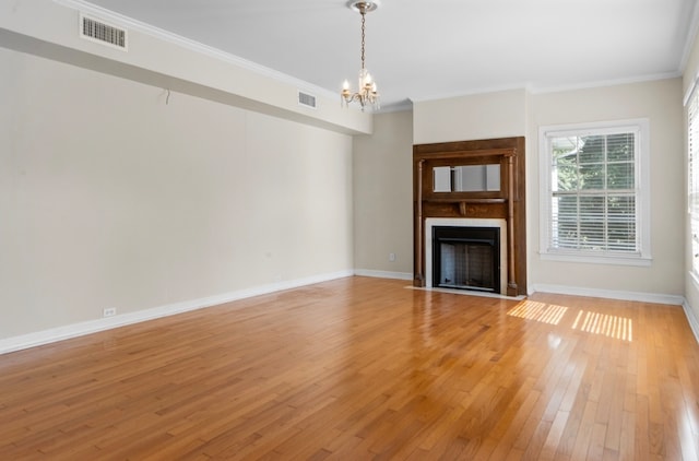 unfurnished living room featuring ornamental molding, hardwood / wood-style floors, and a notable chandelier