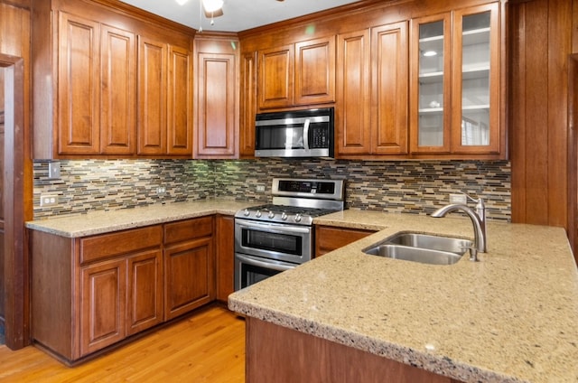 kitchen featuring light stone counters, sink, light hardwood / wood-style flooring, backsplash, and stainless steel appliances