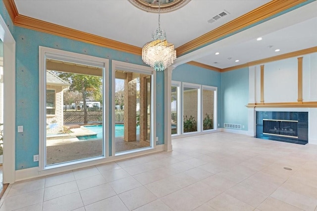 unfurnished living room with ornamental molding, a healthy amount of sunlight, a notable chandelier, and a fireplace