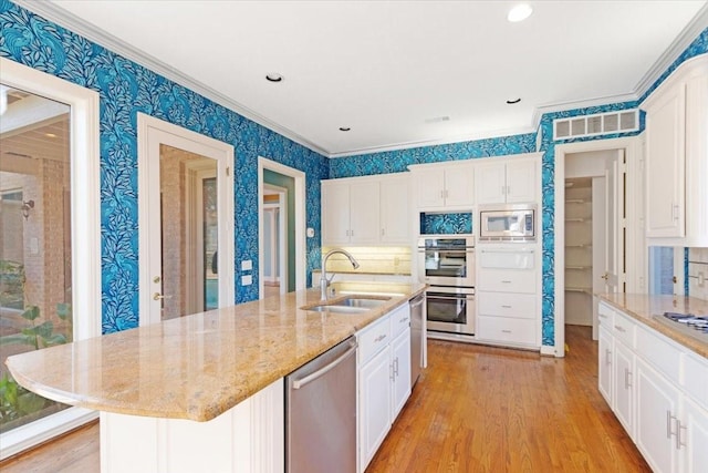 kitchen featuring white cabinetry, appliances with stainless steel finishes, sink, and a center island with sink