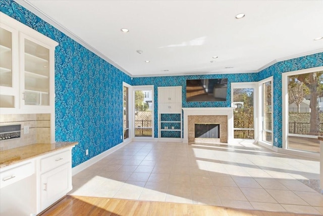 unfurnished living room with crown molding, a healthy amount of sunlight, a premium fireplace, and light tile patterned floors