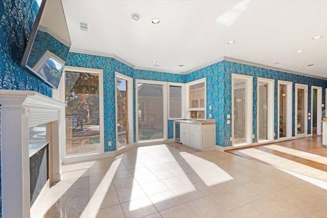 unfurnished living room with ornamental molding and light tile patterned floors