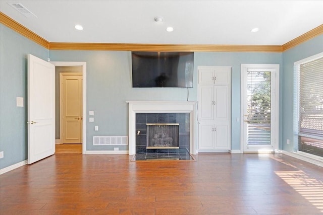 unfurnished living room featuring dark wood-type flooring, ornamental molding, and a tiled fireplace