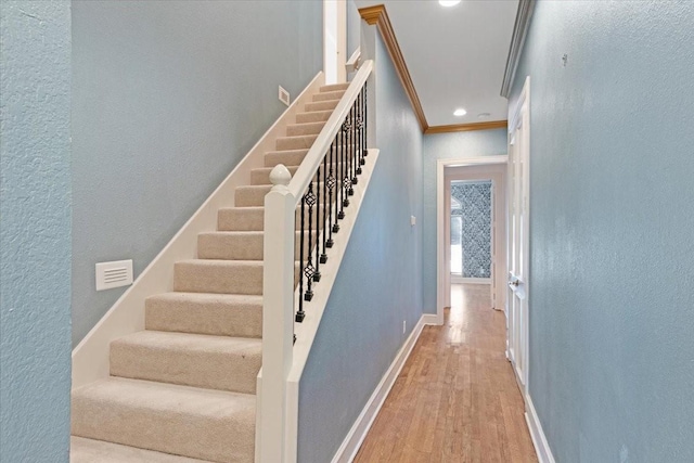 staircase featuring hardwood / wood-style flooring and ornamental molding