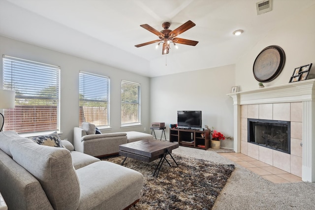 living room with vaulted ceiling, ceiling fan, a tile fireplace, and light tile patterned floors