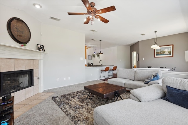 tiled living room featuring ceiling fan and a tile fireplace