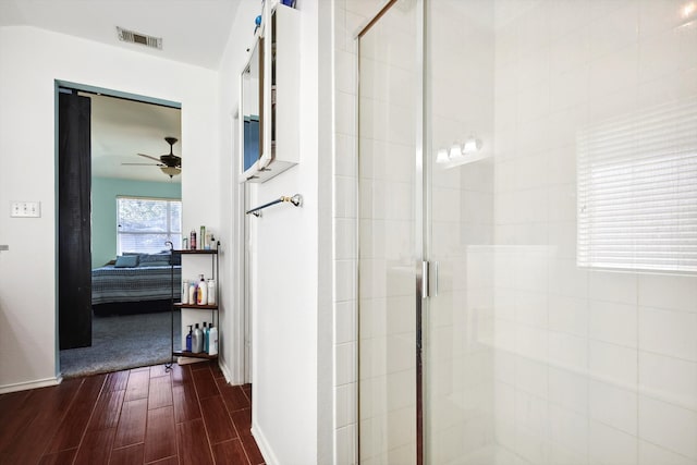 bathroom featuring wood-type flooring, a shower with shower door, and ceiling fan