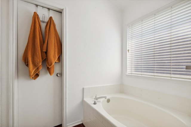 bathroom with tiled bath and a healthy amount of sunlight