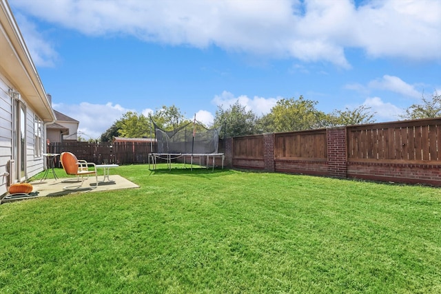 view of yard with a trampoline and a patio