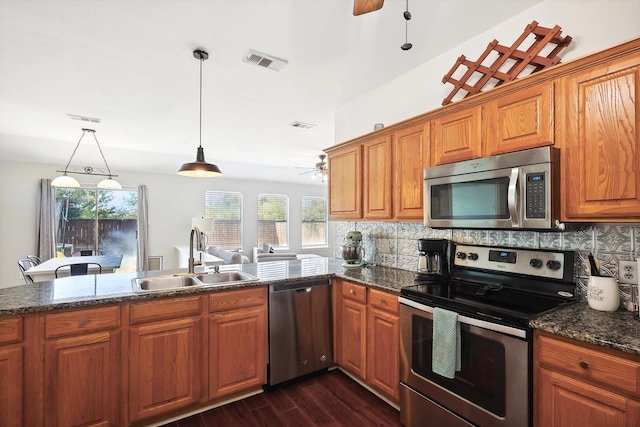 kitchen with decorative backsplash, stainless steel appliances, sink, dark hardwood / wood-style flooring, and pendant lighting