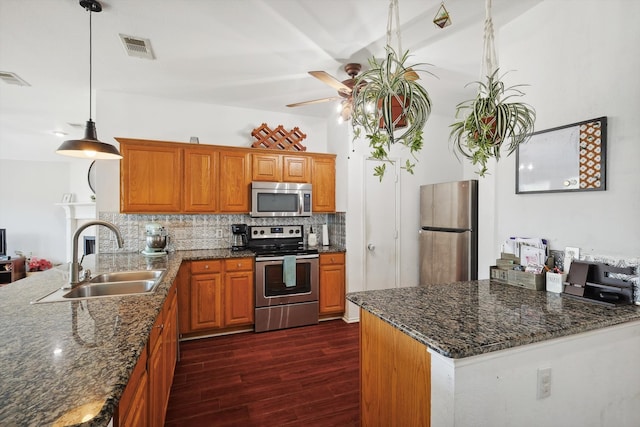 kitchen featuring hanging light fixtures, sink, appliances with stainless steel finishes, dark hardwood / wood-style floors, and decorative backsplash