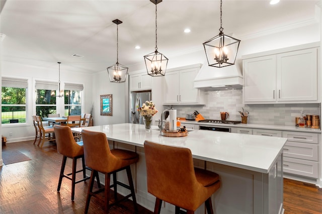 kitchen featuring a large island with sink, appliances with stainless steel finishes, backsplash, and hanging light fixtures