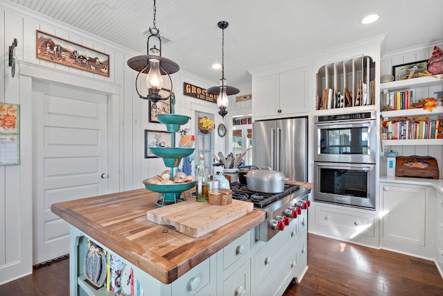 kitchen featuring pendant lighting, a kitchen island, wood counters, stainless steel appliances, and white cabinets