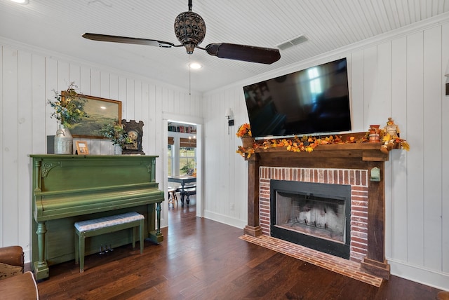 living room featuring a brick fireplace, wooden walls, crown molding, and dark hardwood / wood-style flooring