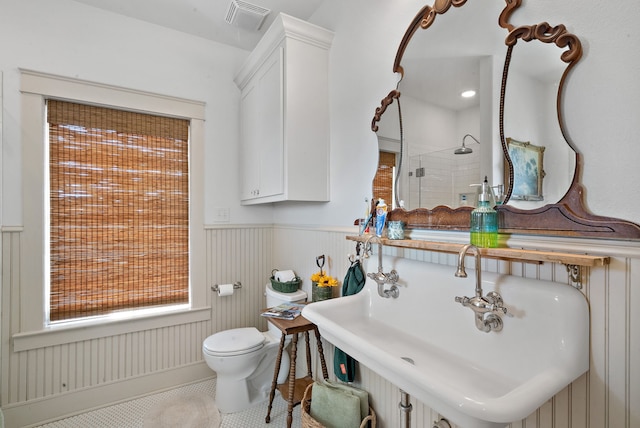 bathroom with tile patterned flooring, a tile shower, sink, and toilet