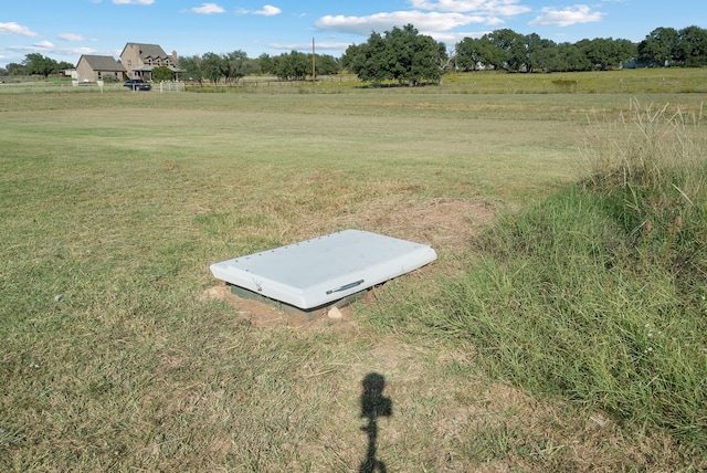 entry to storm shelter featuring a rural view and a lawn