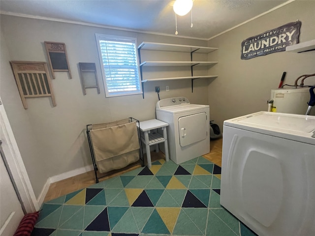 clothes washing area featuring water heater, washing machine and dryer, and crown molding