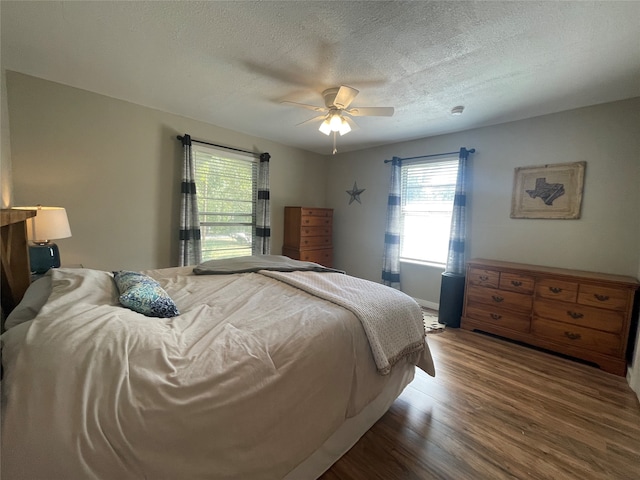 bedroom featuring ceiling fan, wood-type flooring, and a textured ceiling