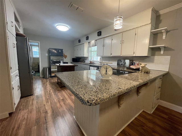 kitchen with decorative light fixtures, stainless steel fridge, kitchen peninsula, and white cabinets