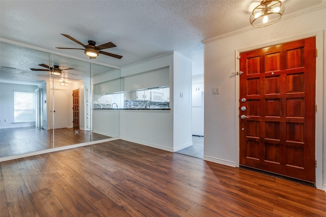 entryway featuring a textured ceiling, dark hardwood / wood-style flooring, and crown molding