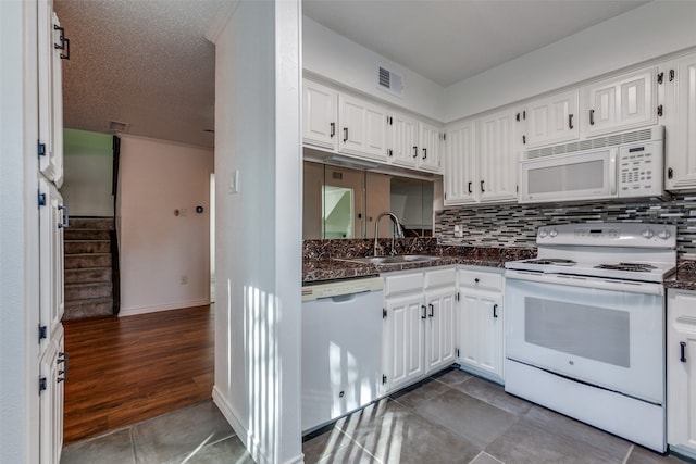 kitchen with backsplash, sink, white appliances, white cabinets, and dark tile patterned floors