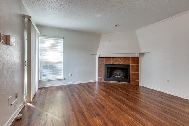 unfurnished living room featuring a textured ceiling, a wealth of natural light, a fireplace, and dark hardwood / wood-style flooring