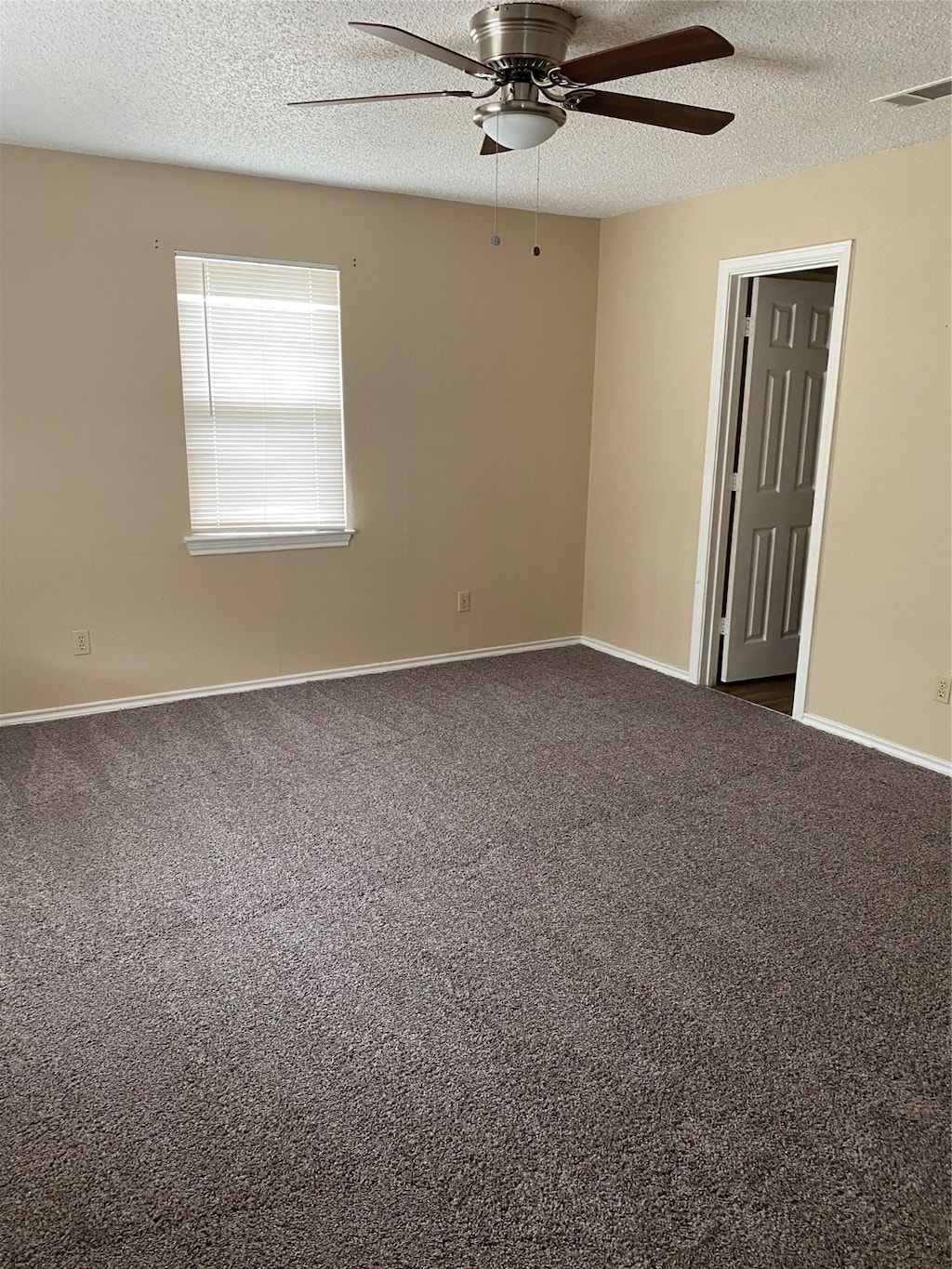 unfurnished room with ceiling fan, carpet flooring, and a textured ceiling