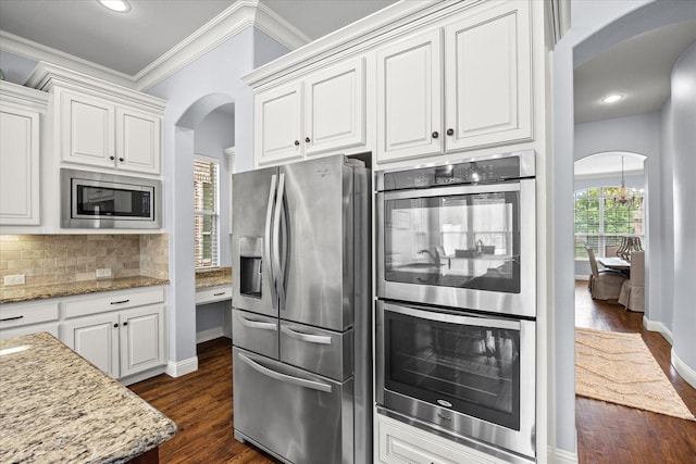 kitchen with backsplash, white cabinetry, stainless steel appliances, and light stone counters