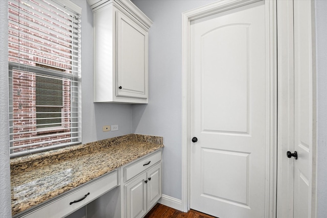 interior space with white cabinets, dark hardwood / wood-style floors, and light stone counters