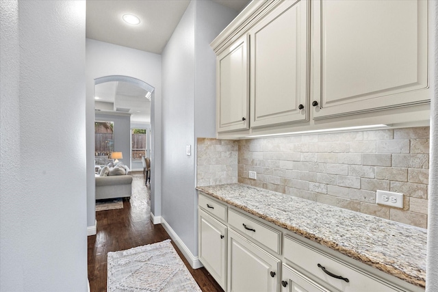 kitchen with white cabinets, backsplash, dark hardwood / wood-style floors, and light stone counters