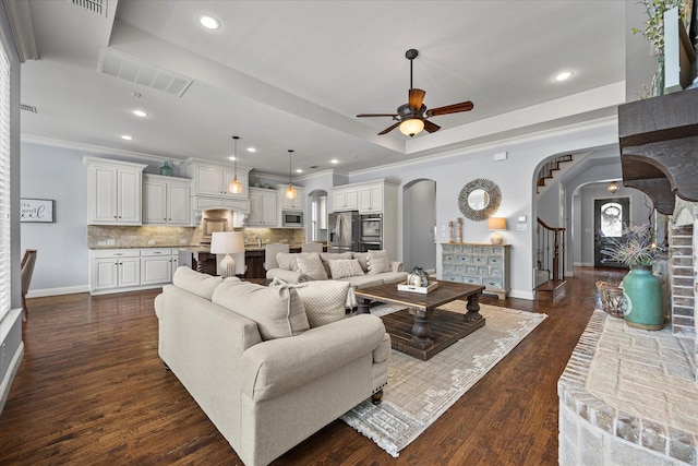 living room with a tray ceiling, ceiling fan, dark hardwood / wood-style flooring, and crown molding