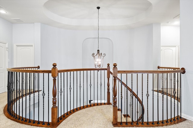 hallway with carpet, an inviting chandelier, and a raised ceiling