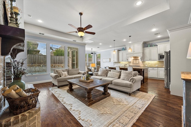 living room with ceiling fan, dark hardwood / wood-style floors, ornamental molding, and a tray ceiling