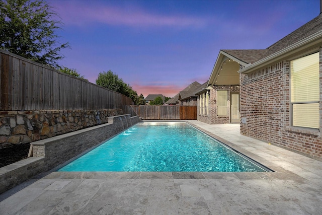 pool at dusk featuring pool water feature