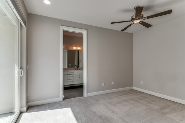 unfurnished bedroom featuring ceiling fan, light carpet, and ensuite bath