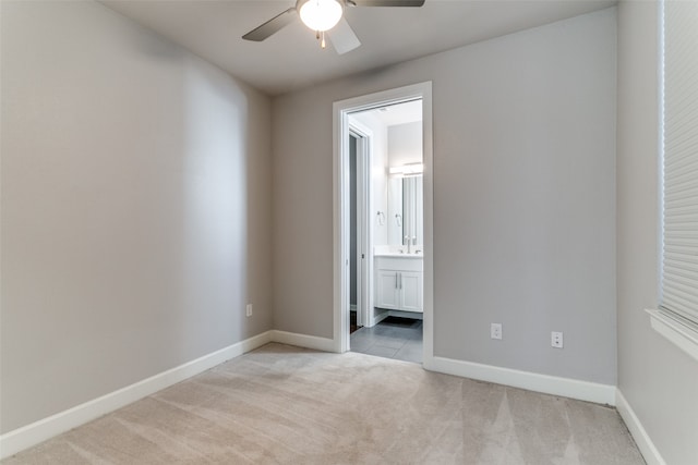 unfurnished bedroom featuring ceiling fan, light carpet, and ensuite bathroom