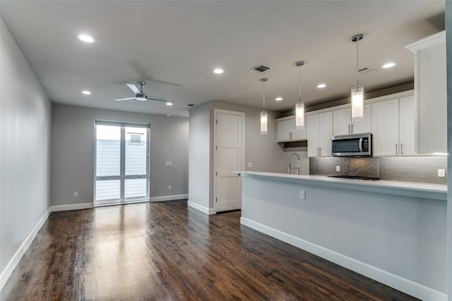 kitchen featuring ceiling fan, white cabinets, pendant lighting, dark wood-type flooring, and decorative backsplash