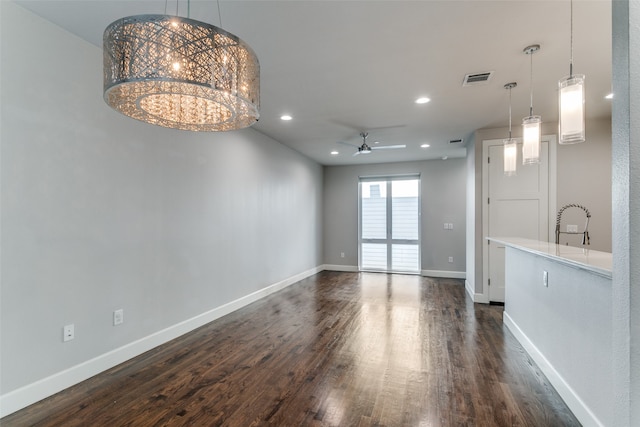 unfurnished living room with ceiling fan with notable chandelier and dark hardwood / wood-style floors