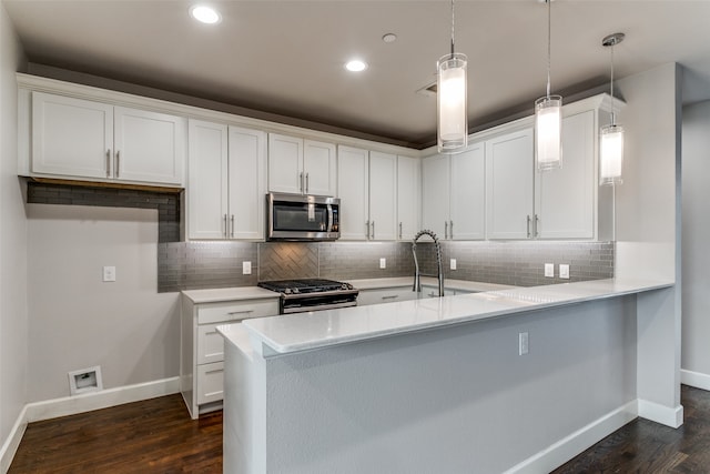 kitchen with dark hardwood / wood-style floors, white cabinets, appliances with stainless steel finishes, and decorative light fixtures