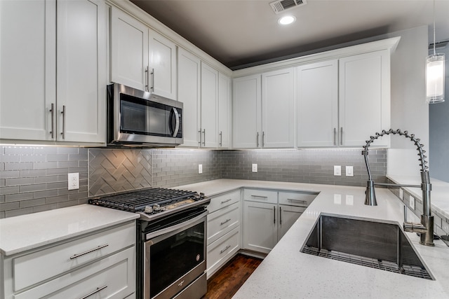 kitchen featuring white cabinets, appliances with stainless steel finishes, sink, and decorative light fixtures